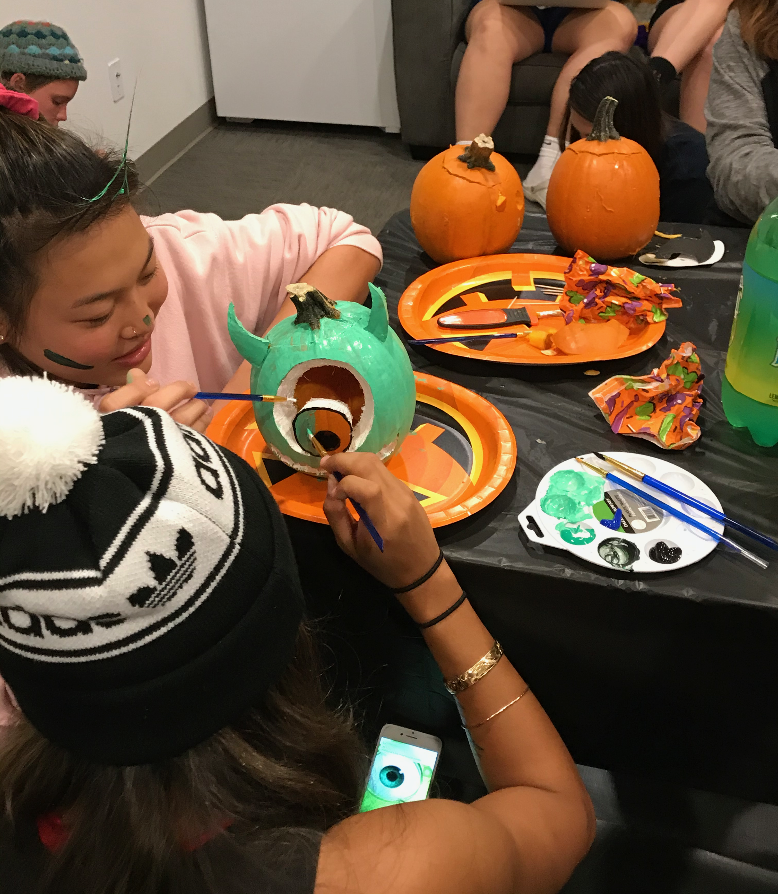 Two residents collaborating to finish decorating a pumpkin