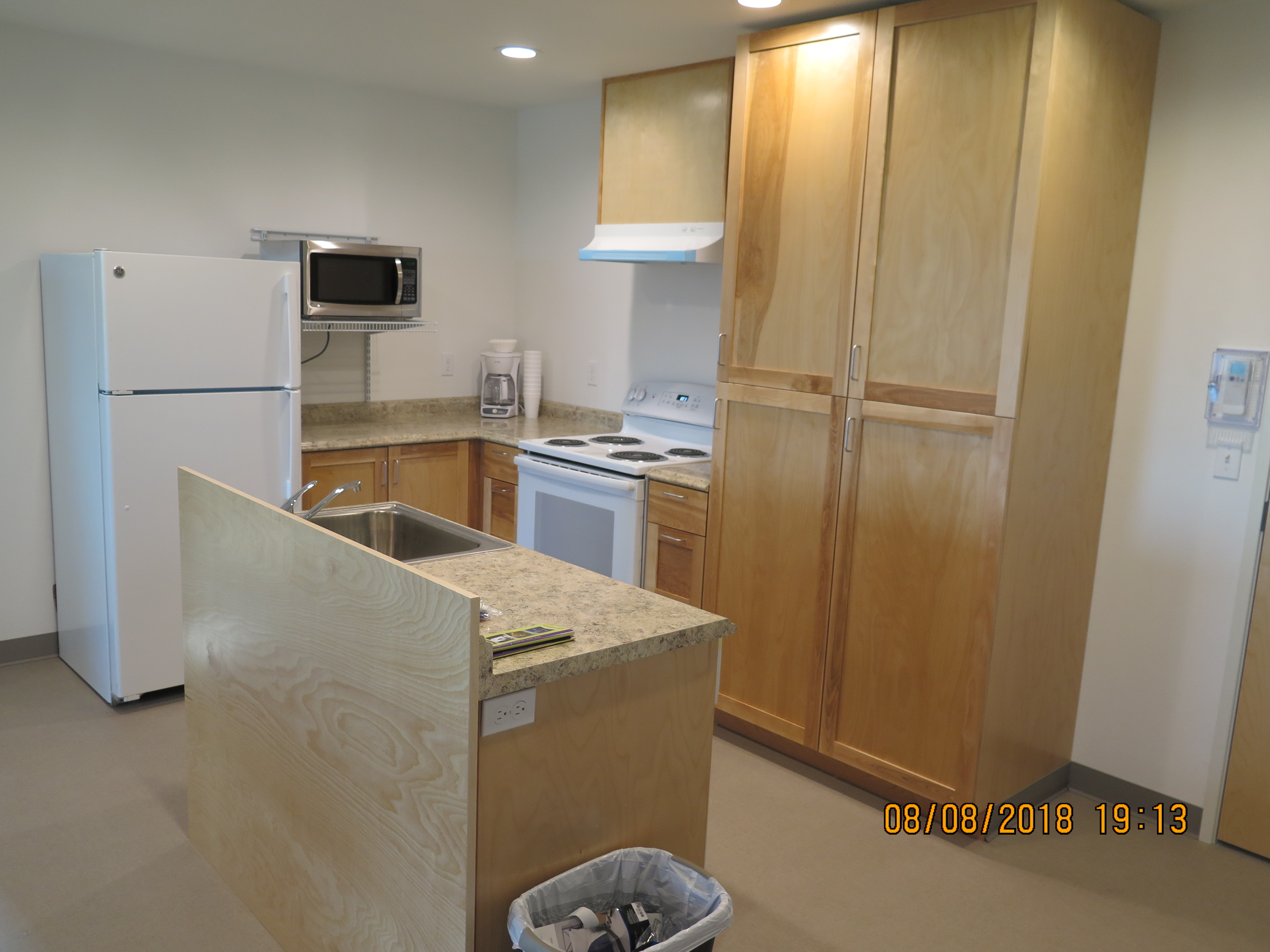 A view of the kitchen, showing sink, refrigerator, stove, microwave, and cabinets.