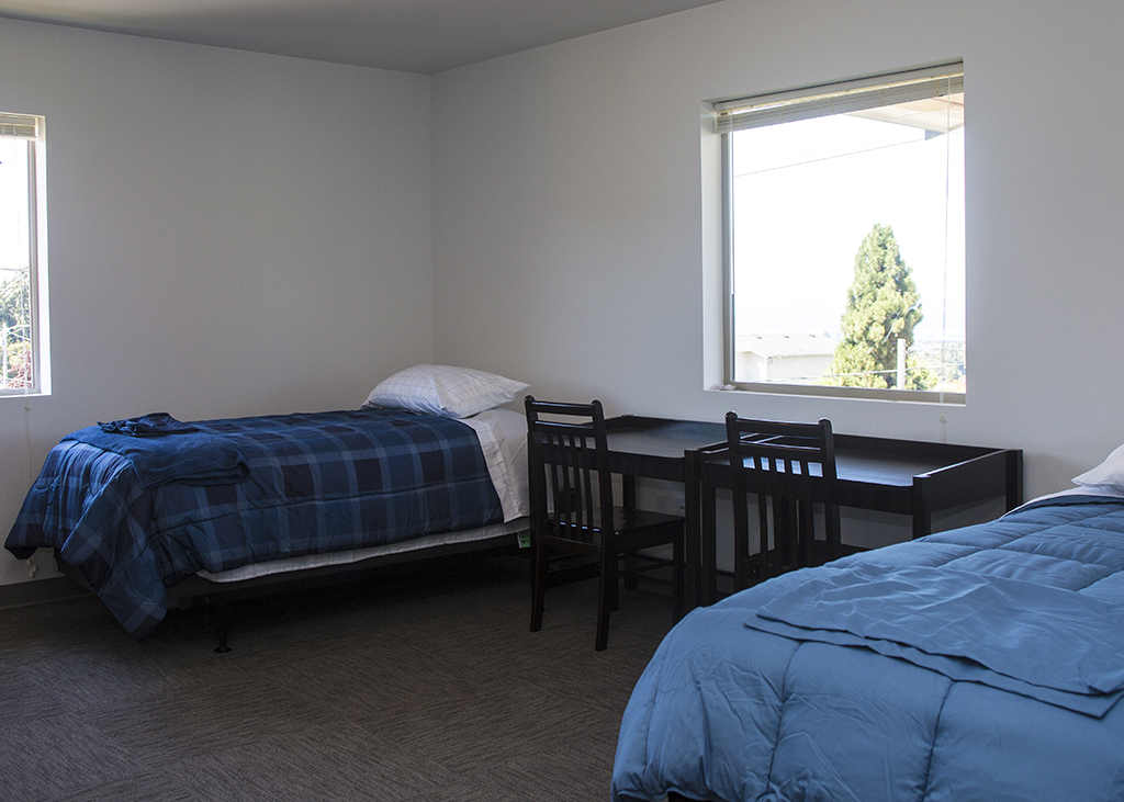 A photo of the bedroom, showing two single beds, two desks, and two big windows.